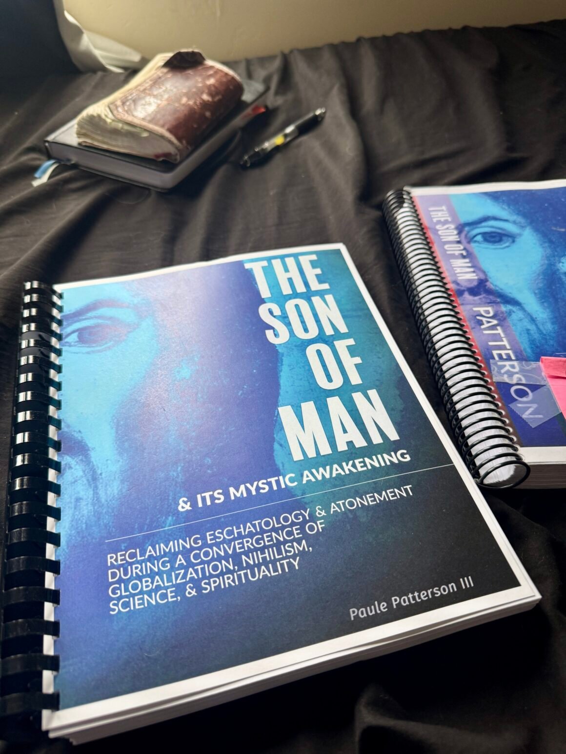 The Son of Man & Its Mystical Awakening: Reclaiming Eschatology and Atonement, two first manuscript drafts, with a bible in the background